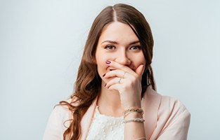 Smiling woman covering her mouth