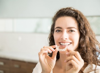 Woman sitting down holding clear aligners in Bend, OR