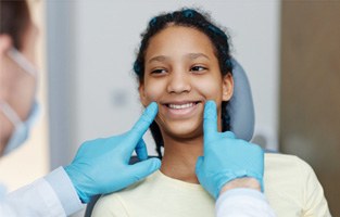 Orthodontist examining patient's smile with blue gloves