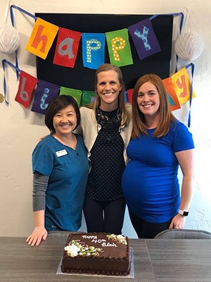 Team members smiling in front of birthday cake