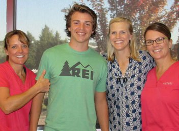 Smiling teen with Herbst appliance with dental team members