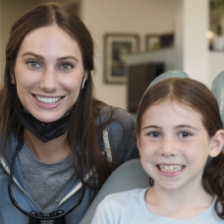 Young girl smiling with an orthodontic team member