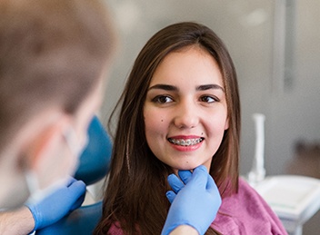 Orthodontist checking smiling patient's braces