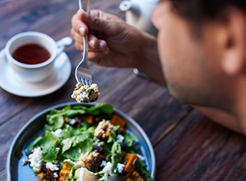 Man sitting at table while eating salad