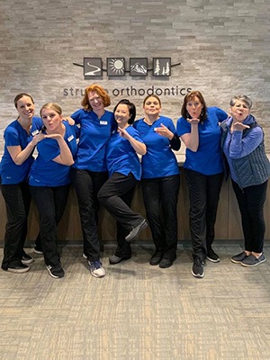 Struble Orthodontics team smiling with office logo behind them