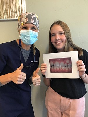 patient holding up picture of her smile with dental team member