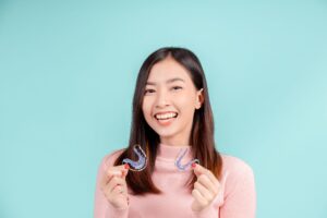 Woman in pink sweater holding a retainer in each hand